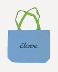 A light blue canvas tote bag with lime green shoulder straps and the word 'clove.' printed in black script across the front, shown on a plain light gray background.