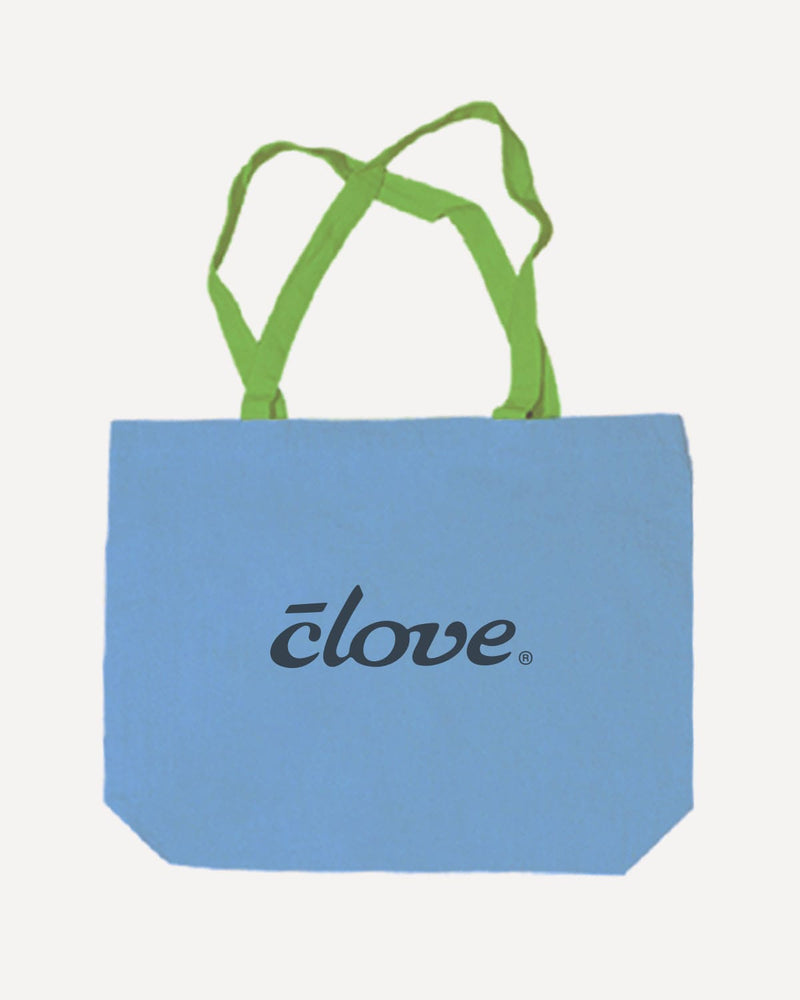 A light blue canvas tote bag with lime green shoulder straps and the word 'clove.' printed in black script across the front, shown on a plain light gray background.