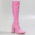 The La Gogo Calf Boot - Pink Wet Look - Street Sole, crafted from stretch vegan patent, is highlighted with its glossy pink finish and striking high block heel against a plain backdrop.