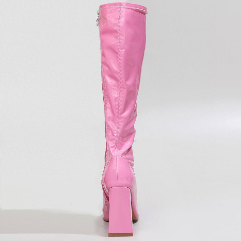 A pink knee-high La Gogo Calf Boot - Pink Wet Look - Street Sole is shown from the back, featuring a chunky block heel, smooth shiny stretch vegan patent finish, and an upper back zipper, set against a plain white background.